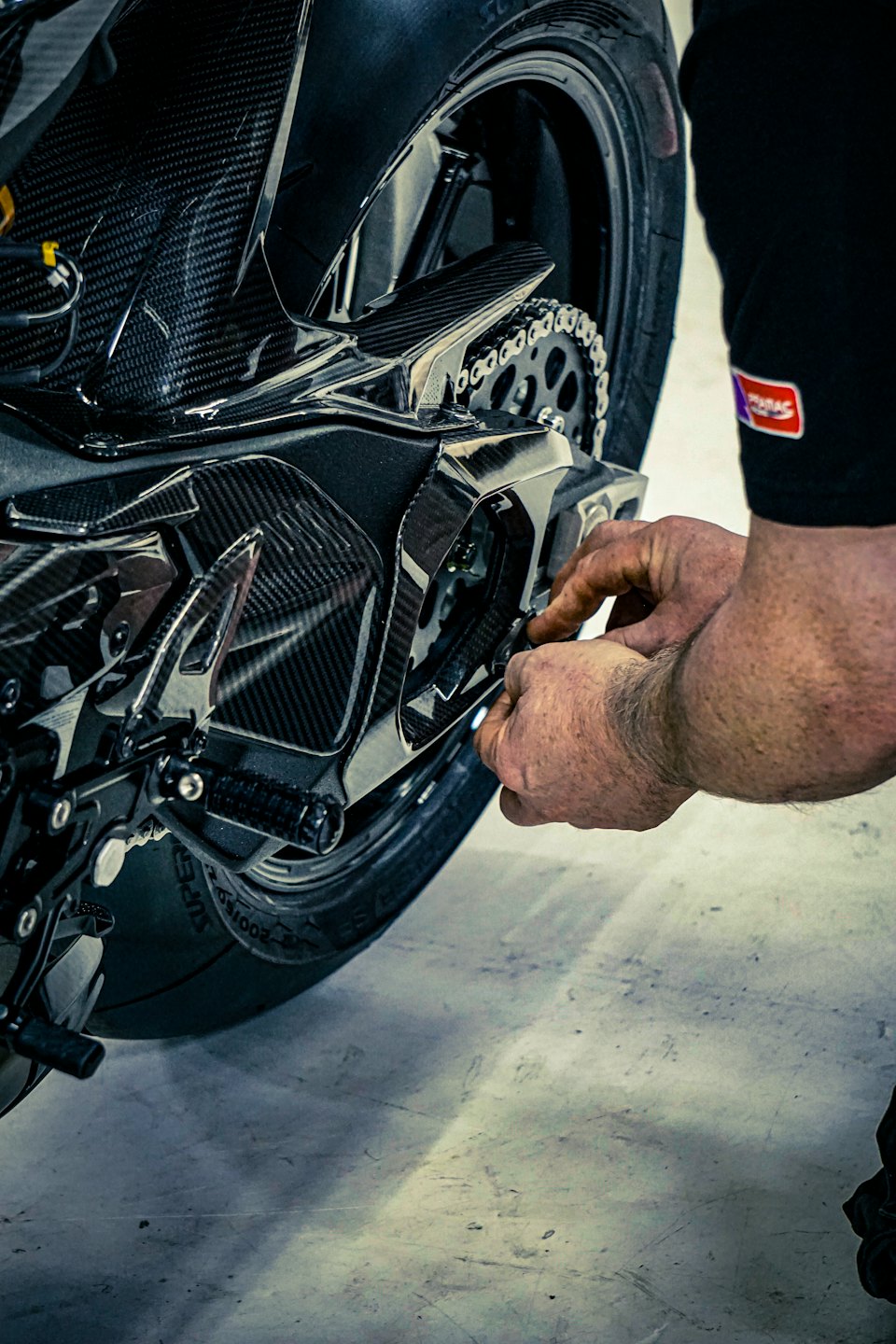 Een monteur stelt de ketting en het tandwiel van een motorfiets af.