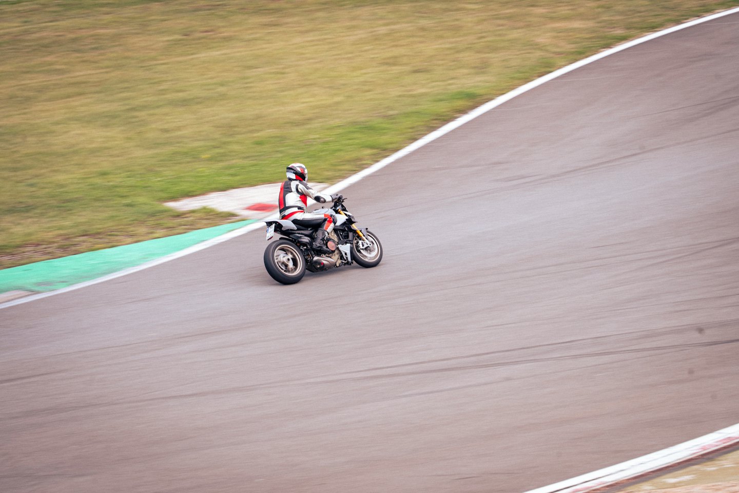 Motorrijder in racekleding die een bocht op het circuit neemt.