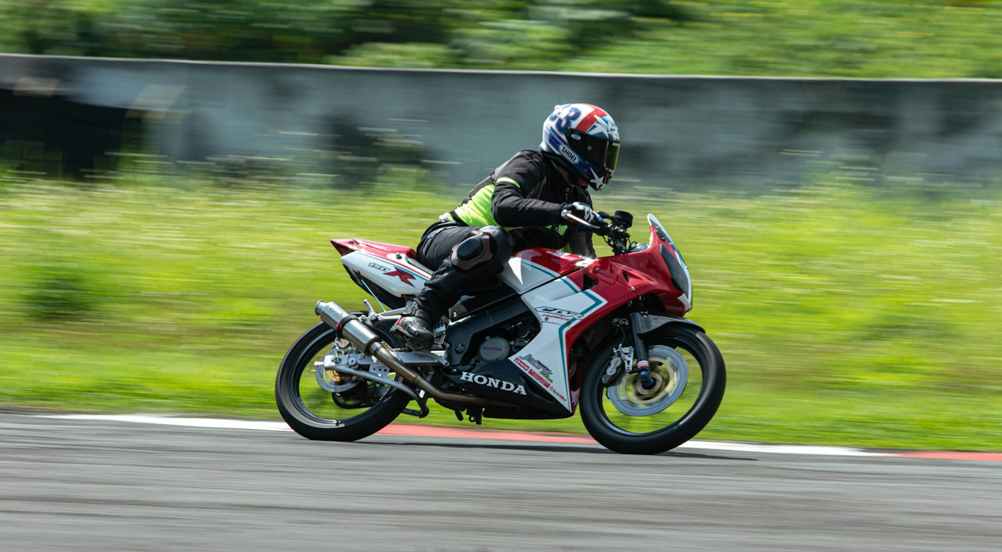 Een motorrijder in racekleding rijdt op een sportmotor op een circuit.